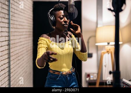 Foto d'inventario di una bella donna nera che canta e usa il microfono in studio musicale. Foto Stock