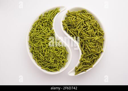 Gli spinaci o il palak SEV sono noodle salate fritte croccanti. Shev o namkeen verde spesso e sottile fatto in casa è un classico spuntino indiano. Servito in una ciotola o in un pl Foto Stock