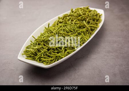 Gli spinaci o il palak SEV sono noodle salate fritte croccanti. Shev o namkeen verde spesso e sottile fatto in casa è un classico spuntino indiano. Servito in una ciotola o in un pl Foto Stock