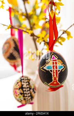 La sistemazione delle tradizionali uova di Pasqua 'Blatnice' decorate da Marie Cihakova e Forsythia fiorente, Brno, Repubblica Ceca, il 30 marzo 2021. (C Foto Stock