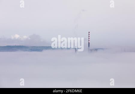 Aghada, Cork, Irlanda. 31 marzo, 2021.il sole di mattina presto comincia a disapare la nebbia di mare che avvolge i serbatoi di deposito alla raffineria di petrolio e alla stazione elettrica generatrice in Aghada, Co. Cork, Irlanda. - credito; David Creedon / Alamy Live News Foto Stock