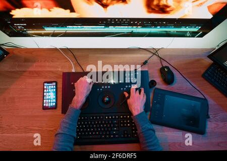 Male Video Editor Hands lavora con filmati o video sul suo pannello di controllo del Personal computer, lavora in Creative Office Studio o a casa. Luci al neon Foto Stock