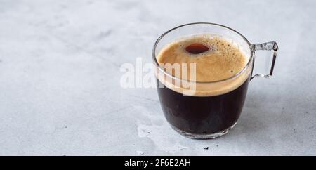 Espresso caldo fresco in una tazza di vetro trasparente. Caffè nero su sfondo di pietra - immagine Foto Stock