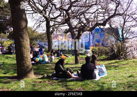 Mentre la chiusura della Gran Bretagna facilita le famiglie rilassarsi all'ombra degli alberi, Southend Cliff Gardens, Southend-on-Sea, Essex, Gran Bretagna, 30 Marzo 2021 Foto Stock