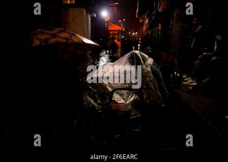 Kathmandu, Nepal. 31 Marzo 2021. Un venditore si copre all'interno di un foglio di plastica durante le precipitazioni a Basantapur Durbar Square, un sito patrimonio dell'umanità dell'UNESCO a Kathmandu, Nepal, mercoledì 31 marzo 2021. Credit: Skanda Gautam/ZUMA Wire/Alamy Live News Foto Stock