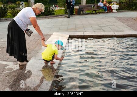 YAROSLAVL, RUSSIA-4 AGOSTO 2018: Una nonna o una bambina anziana cammina con un ragazzino lungo l'argine vicino alla fontana in una giornata estiva. Emban Foto Stock