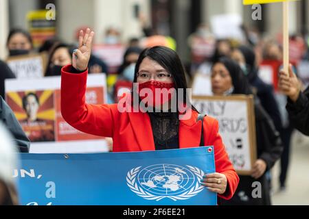 Londra, Regno Unito. 31 Marzo 2021. Un protester femminile in marcia fa il saluto a tre dita della resistenza. I manifestanti si sono riuniti in Piazza del Parlamento - indossando maschere facciali e osservando le distanze sociali - prima di marciare all'ambasciata cinese in solidarietà con il popolo del Myanmar contro il colpo di stato militare e le uccisioni di civili. I discorsi sono stati fatti fuori dall'ambasciata. Dall'inizio del colpo di stato militare del 1° febbraio, oltre 520 persone sono state uccise in Myanmar dalle forze di sicurezza. Sabato scorso è stato il giorno più violento in cui sono state uccise più di 100 persone. Credito: Joshua Wi Foto Stock