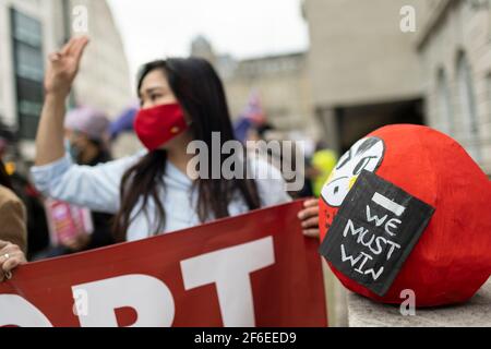 Londra, Regno Unito. 31 Marzo 2021. Un protester femminile rende il saluto a tre dita della resistenza. I manifestanti si sono riuniti in Piazza del Parlamento - indossando maschere facciali e osservando le distanze sociali - prima di marciare all'ambasciata cinese in solidarietà con il popolo del Myanmar contro il colpo di stato militare e le uccisioni di civili. I discorsi sono stati fatti fuori dall'ambasciata. Dall'inizio del colpo di stato militare del 1° febbraio, oltre 520 persone sono state uccise in Myanmar dalle forze di sicurezza. Sabato scorso è stato il giorno più violento in cui sono state uccise più di 100 persone. Credito: Joshua Windsor/Ala Foto Stock