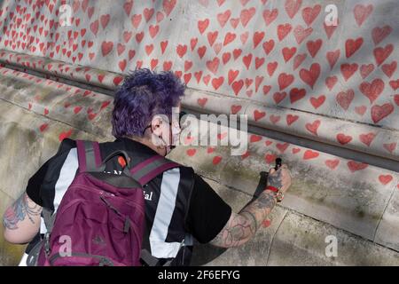I cuori rossi che formano il National Covid Memorial Wall, un tributo alle oltre 150,000 vittime britanniche della pandemia di Coronavirus. La famiglia e gli amici delle vittime di Covid-19 hanno iniziato a lavorare sul muro situato fuori dall'ospedale St Thomas, e che si affaccia alla Camera del Parlamento a Westminster, il 30 marzo 2021, a Londra, Inghilterra. Lo scorso anno il primo Ministro Boris Johnson è stato trattato per Covid a St Thomas. Foto Stock