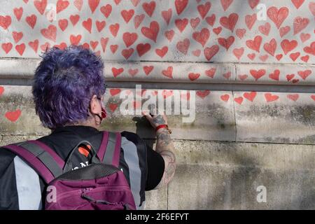 I cuori rossi che formano il National Covid Memorial Wall, un tributo alle oltre 150,000 vittime britanniche della pandemia di Coronavirus. La famiglia e gli amici delle vittime di Covid-19 hanno iniziato a lavorare sul muro situato fuori dall'ospedale St Thomas, e che si affaccia alla Camera del Parlamento a Westminster, il 30 marzo 2021, a Londra, Inghilterra. Lo scorso anno il primo Ministro Boris Johnson è stato trattato per Covid a St Thomas. Foto Stock