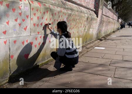 I cuori rossi che formano il National Covid Memorial Wall, un tributo alle oltre 150,000 vittime britanniche della pandemia di Coronavirus. La famiglia e gli amici delle vittime di Covid-19 hanno iniziato a lavorare sul muro situato fuori dall'ospedale St Thomas, e che si affaccia alla Camera del Parlamento a Westminster, il 30 marzo 2021, a Londra, Inghilterra. Lo scorso anno il primo Ministro Boris Johnson è stato trattato per Covid a St Thomas. Foto Stock