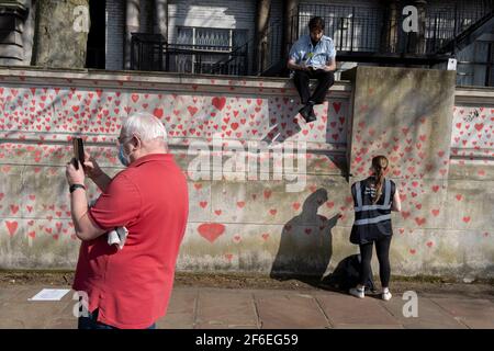 I cuori rossi che formano il National Covid Memorial Wall, un tributo alle oltre 150,000 vittime britanniche della pandemia di Coronavirus. La famiglia e gli amici delle vittime di Covid-19 hanno iniziato a lavorare sul muro situato fuori dall'ospedale St Thomas, e che si affaccia alla Camera del Parlamento a Westminster, il 30 marzo 2021, a Londra, Inghilterra. Lo scorso anno il primo Ministro Boris Johnson è stato trattato per Covid a St Thomas. Foto Stock
