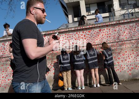 I cuori rossi che formano il National Covid Memorial Wall, un tributo alle oltre 150,000 vittime britanniche della pandemia di Coronavirus. La famiglia e gli amici delle vittime di Covid-19 hanno iniziato a lavorare sul muro situato fuori dall'ospedale St Thomas, e che si affaccia alla Camera del Parlamento a Westminster, il 30 marzo 2021, a Londra, Inghilterra. Lo scorso anno il primo Ministro Boris Johnson è stato trattato per Covid a St Thomas. Foto Stock
