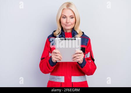 Foto di seria messa a fuoco vecchia donna paramedica professionale guardare tenere lavoratore tablet isolato su sfondo grigio Foto Stock