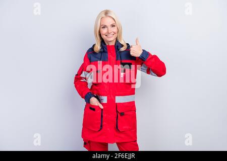 Foto di una simpatica bella signora messa mano in tasca show pollice su sorriso togoloso isolato su sfondo grigio Foto Stock