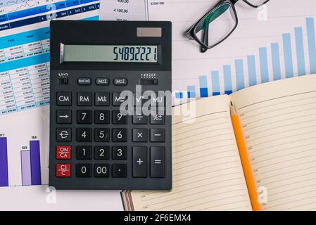 Calcolatrice, aprire il notebook e il grafico finanziario. Tabella con numeri e dati analitici. Previsione dell'aumento o della diminuzione delle azioni. Analisi delle vendite figura Foto Stock