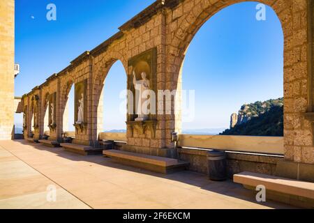 Vista dei portici con statue di santi nelle colonne della Plaza de Santa Maria nel complesso turistico-religioso del Monastero di Montserrat, Foto Stock