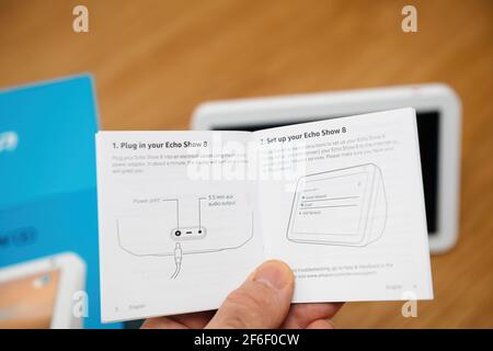 Mano maschile che legge il manuale di istruzioni di Amazon Echo Show 8 dispositivo smart speaker con Amazon Alexa - plug-in e. impostare la guida Foto Stock