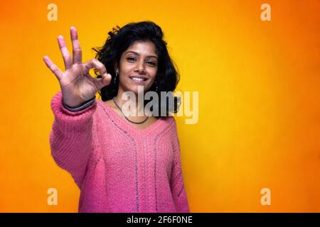 Bella Sri Lanka ragazza posa in piedi con giallo luminoso sfondo- La giovane donna sorride facendo bene Foto Stock