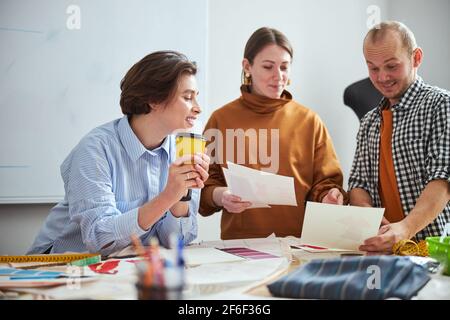 Enthusiastic colleagues looking at the drawings and smiling Foto Stock