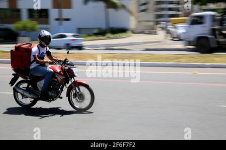 salvador, bahia, brasile - 6 gennaio 2021: L'uomo che consegna il cibo da applicazione è visto che cavalcano una motocicletta sulla strada nel quartiere di Pituba in th Foto Stock