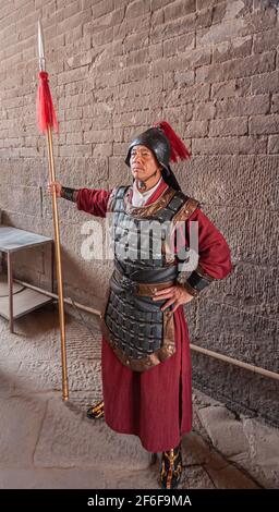 Xian, Cina - 30 aprile 2010: Cerimonia alla porta Nord delle Mura della Citta' di Shuncheng. Closeup di guardia armata all'ingresso con lancia, casco e garb di maroon. Foto Stock