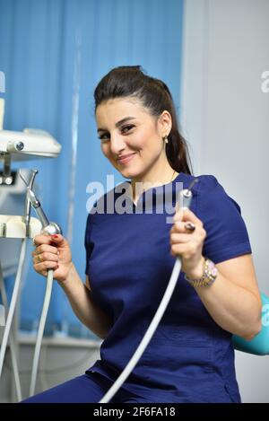 Ritratto di dentista dottoressa che tiene gli attrezzi di lavoro e sorridente Foto Stock