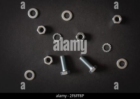 Bulloneria - bulloni, dadi, rondelle, viti su fondo grigio nero Foto Stock
