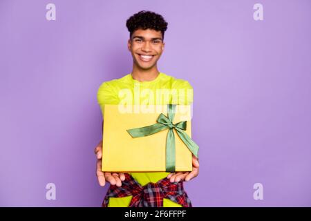 Ritratto fotografico di giovane ricciolo che tiene presente scatola con nastro sorridente alla festa isolato su sfondo color porpora pastello Foto Stock