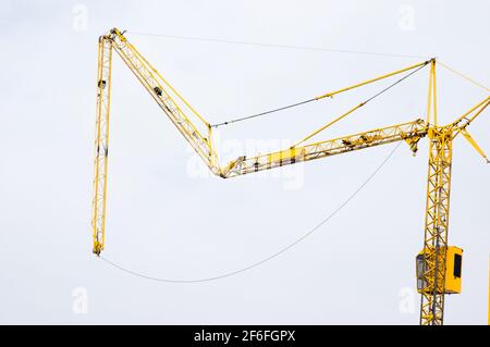 Il braccio delle gru a torre gialle si ripiega sul cantiere Foto Stock