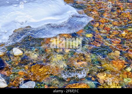 Concetto di bellezza e grandezza della natura: Acque cristalline in un fiume di montagna con un bordo di ghiaccio spettacolare Foto Stock