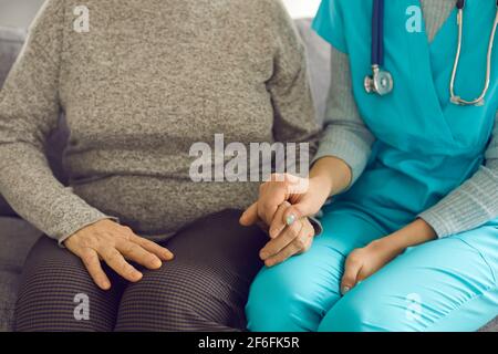 Dottore o infermiera che tiene la mano del paziente anziano come segno di assistenza e supporto. Foto Stock