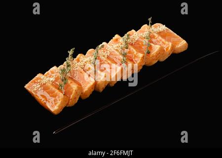 Terreno Tataki di salmone, salsa kimchi, salsa Aroy-D, erba cipollina, semi di sesamo. Isolato su sfondo nero Foto Stock