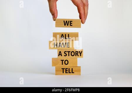 Abbiamo tutti una storia da raccontare Symbol. Blocchi di legno con parole 'abbiamo tutti una storia da raccontare'. Mano uomo d'affari. Splendido sfondo bianco. Business, po Foto Stock
