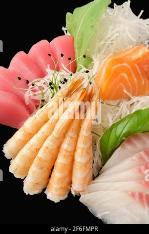 Salmone sashimi assortito, spigola, tonno, gamberi tigre. Cibo giapponese. Isolato su sfondo nero Foto Stock