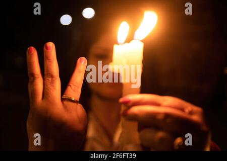 Kathmandu, Nepal. 31 Marzo 2021. Un protestante che tiene una candela bruciante mentre fa il saluto a tre dita assiste ad una veglia a lume di candela per coloro che sono morti in proteste durante il colpo di stato militare del Myanmar presso i locali di Basantapur Durbar Square, un sito patrimonio mondiale dell'UNESCO. Protesta contro il colpo di Stato militare e la violenza in atto in Myanmar. (Foto di Prabin Ranabhat/SOPA Images/Sipa USA) Credit: Sipa USA/Alamy Live News Foto Stock