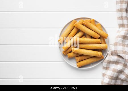 Cialde dolci rotolano sul piatto sul tavolo bianco. Vista dall'alto. Foto Stock