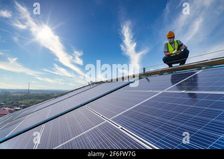 Tecnico asiatico che controlla la manutenzione dei pannelli solari sul tetto, energia solare Foto Stock