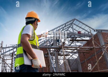 Tecnico tecnico tecnico che cerca la struttura del tetto e analizza un Unfinished Progetto di costruzione Foto Stock