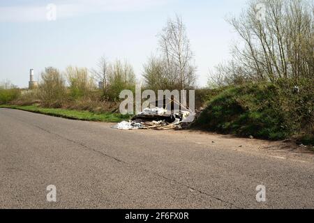 I rifiuti di scarico illegalmente volano ribaltati su una corsia di paese Foto Stock