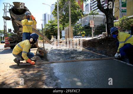 salvador, bahia, brasile - 9 dicembre 2020: Lavori di muratori sulla costruzione di un pavimento in cemento nella costruzione di un percorso di trasporto nella città di SA Foto Stock