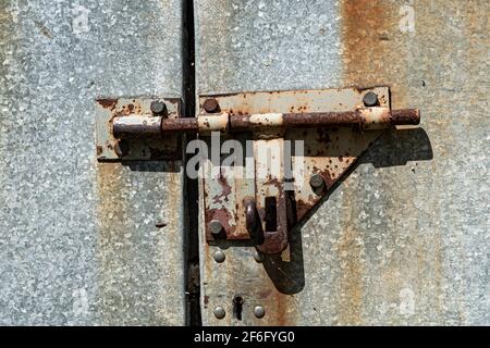 Vecchia porta in metallo arrugginita arrugginita con chiusura e chiusura. Primo piano della serratura vintage arrugginita sulla porta chiusa Foto Stock