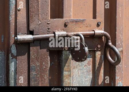 Vecchia porta in metallo arrugginita arrugginita con serratura e lucchetto. Primo piano della serratura vintage arrugginita sulla porta chiusa Foto Stock
