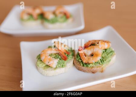 Sano antipasto di bruschetta con vista closeup di gamberi guacamole. Gamberi fritti e avocado schiacciato su pane tostato Foto Stock