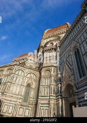 Cattedrale di Santa Maria del Fiore. Landmark 1200 cattedrale colorata facciata laterale in marmo vista soleggiata con sfondo blu cielo. Viaggi in Italia Foto Stock