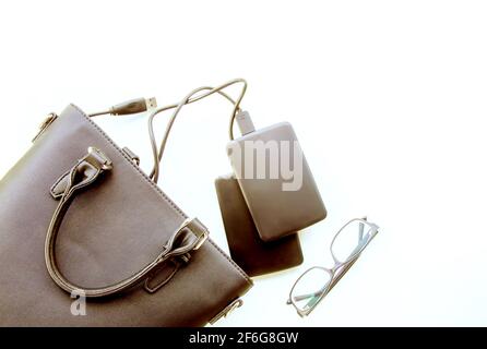 Composizione con sacchetto nero, dischi rigidi esterni e bicchieri su sfondo bianco. Dettagli aziendali. Foto Stock