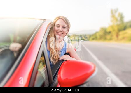 Felice bella donna sta guidando una macchina rossa. Foto Stock