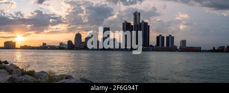 Detroit Skyline Fom Windsor, Canada: Mentre il sole tramonta, gli alti edifici dominati dalla torre GM di Detroit diventano parzialmente sagomati contro un cielo pieno di nuvole. Foto Stock