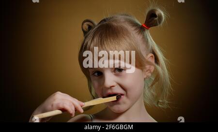 Gioiosa bambina sorridente con faccia sporca da fusa cioccolato su sfondo scuro in studio Foto Stock