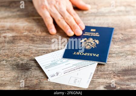 Clarksburg, MD, USA 03-29-2021: Una persona caucasica sta mostrando i suoi documenti di viaggio all'aeroporto, inclusi passaporto statunitense, carta d'imbarco e COVID vaccinati Foto Stock